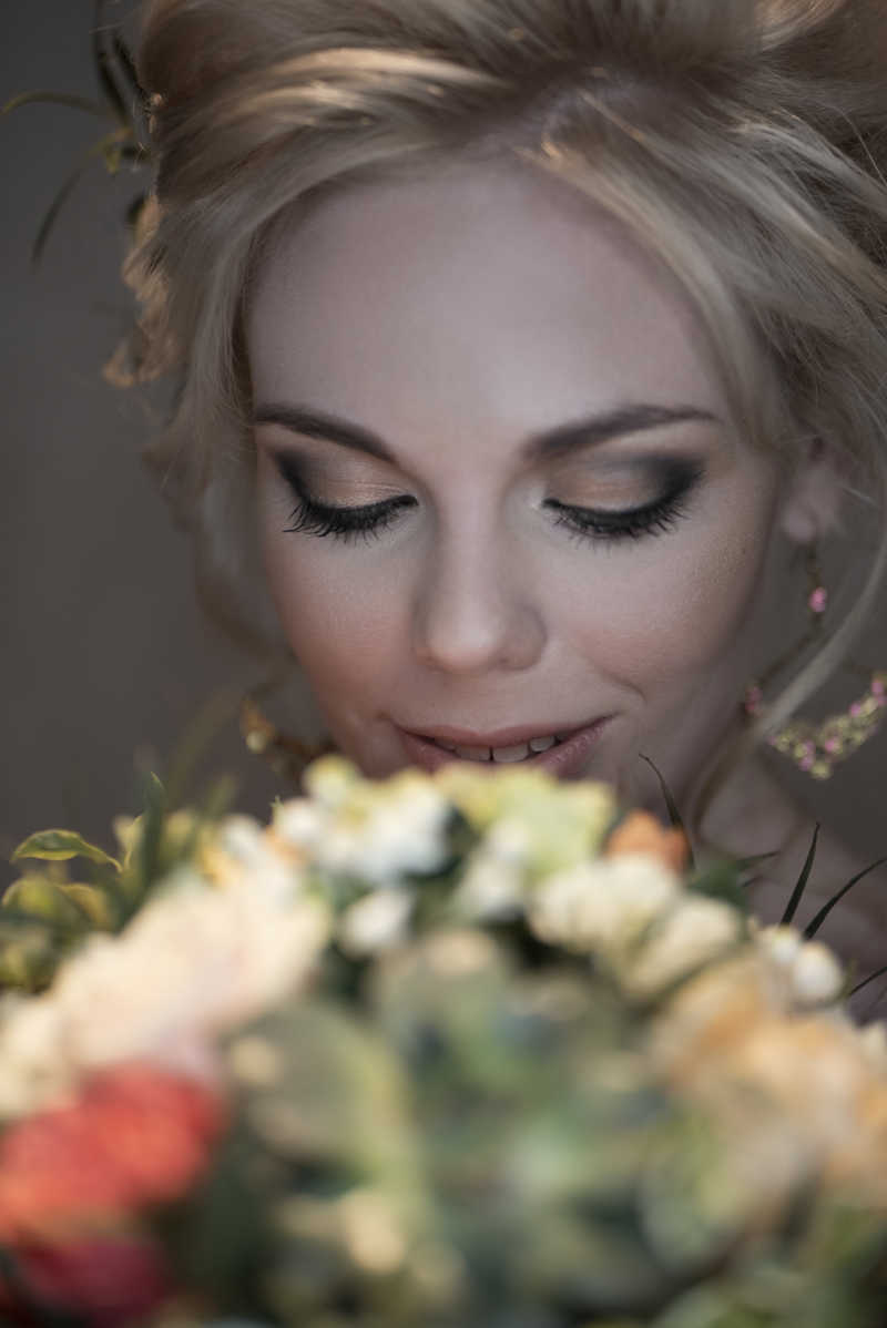 幸福的微笑的新娘看着她的花束
