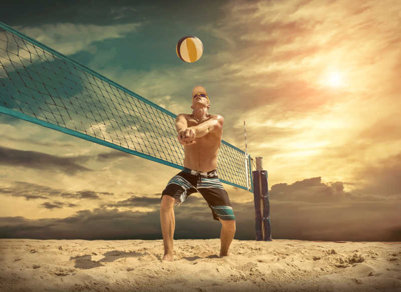 日落时分在沙滩上打排球的男人