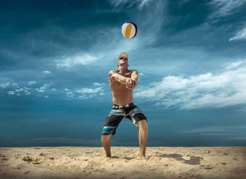 蓝天下在沙滩上一个男排运动员在打排球
