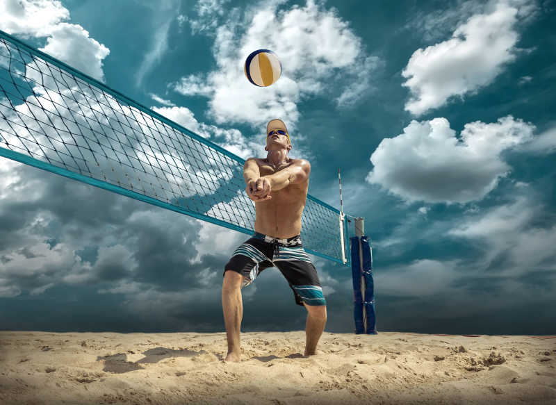 蓝色天空下在沙滩上男人在进行打排球的活动
