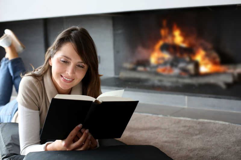 在壁炉旁趴着欣赏书籍的女士