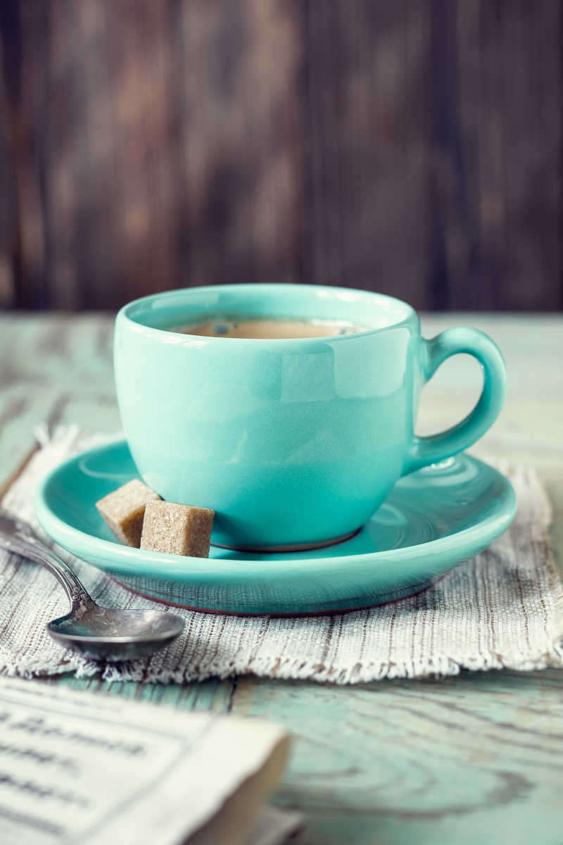 桌子上的盛有咖啡的青色咖啡杯