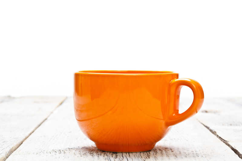 木桌上的橙色咖啡杯