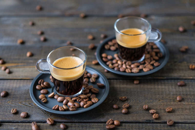 两杯浓咖啡和咖啡豆放在木桌上