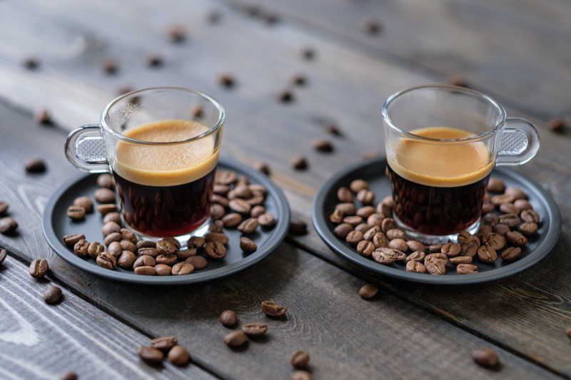 木桌上的两杯浓咖啡和咖啡豆