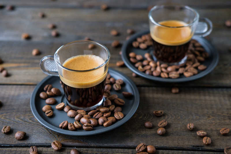 两杯浓咖啡和咖啡豆在一张木桌上