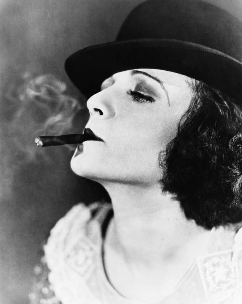一名戴着帽子抽着雪茄的年轻女子的黑白肖像