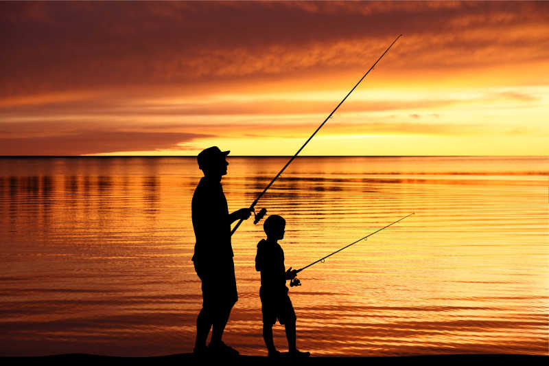 一个人带着一个小孩在湖边钓鱼