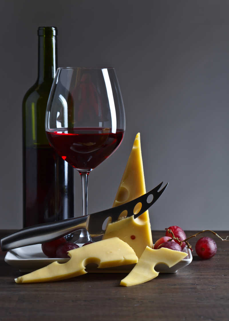 旧木桌上的奶酪和红酒瓶
