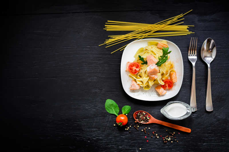 黑色餐桌上的三文鱼意大利面