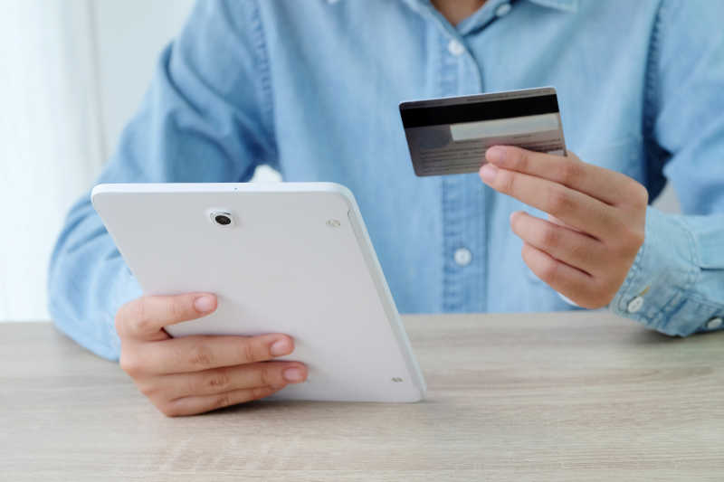 一个人使用信用卡在平板上购物