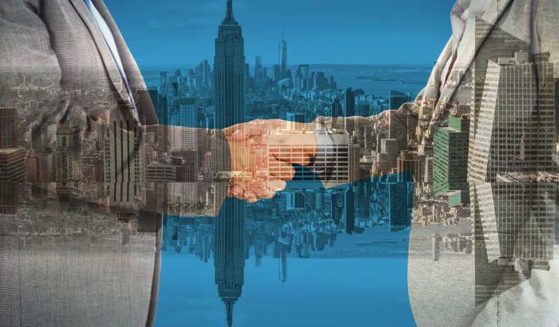 两个人握手在合成的城市建筑背景下