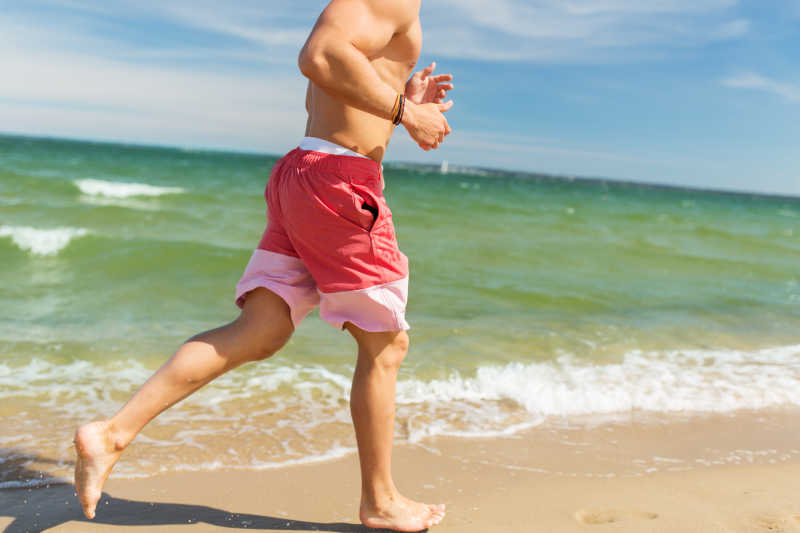 沿着海滩慢跑的年轻人