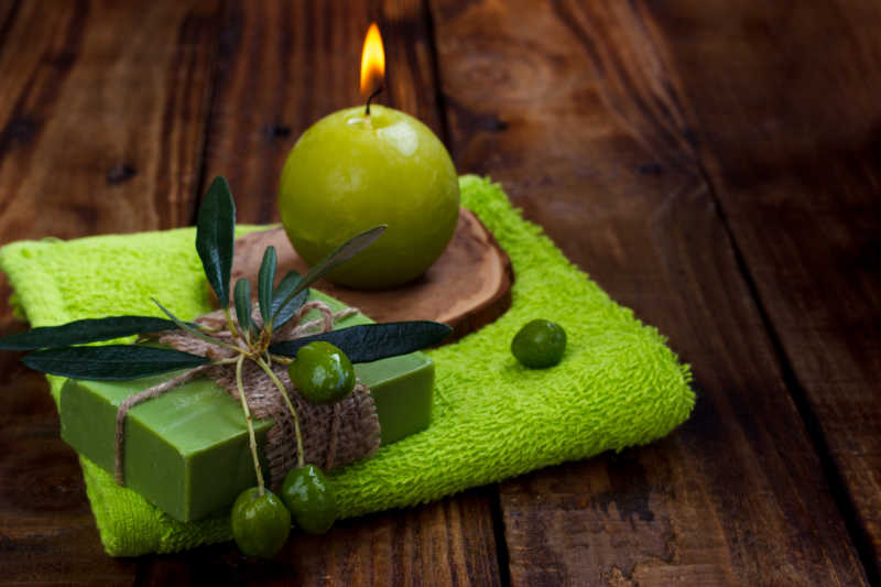 棕色木板上的而绿色毛巾和蜡烛