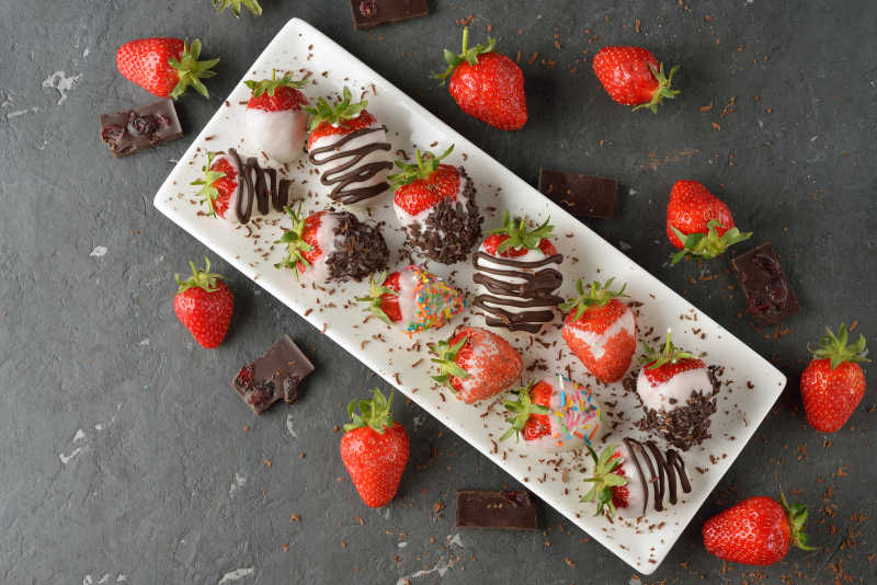 长方形的盘子里的草莓包裹着巧克力