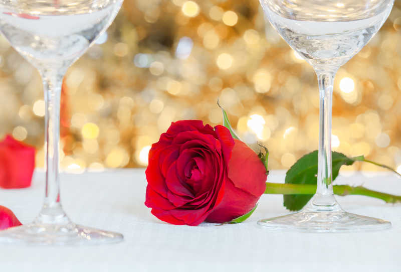 桌子上的浪漫晚餐准备酒杯和红玫瑰