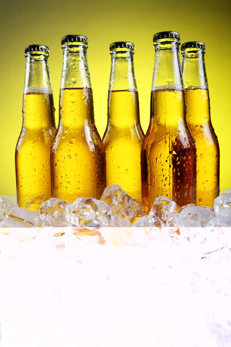 黄色背景下冰块上的啤酒