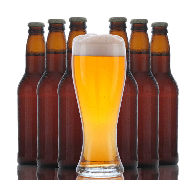 一杯泡沫状的啤酒与六个棕色的瓶子