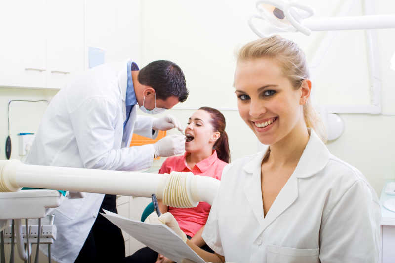 牙科诊所里的牙医检查牙齿和微笑的护士