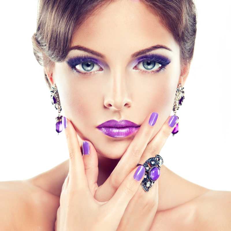 戴着紫色戒指耳坠和紫色的指甲油口红的女模特