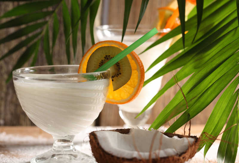 棕榈叶旁的酒杯里的椰汁