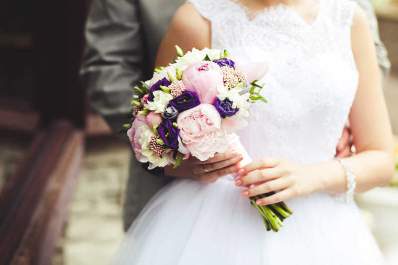 新婚夫妇手里拿着一束捧花的特写镜头