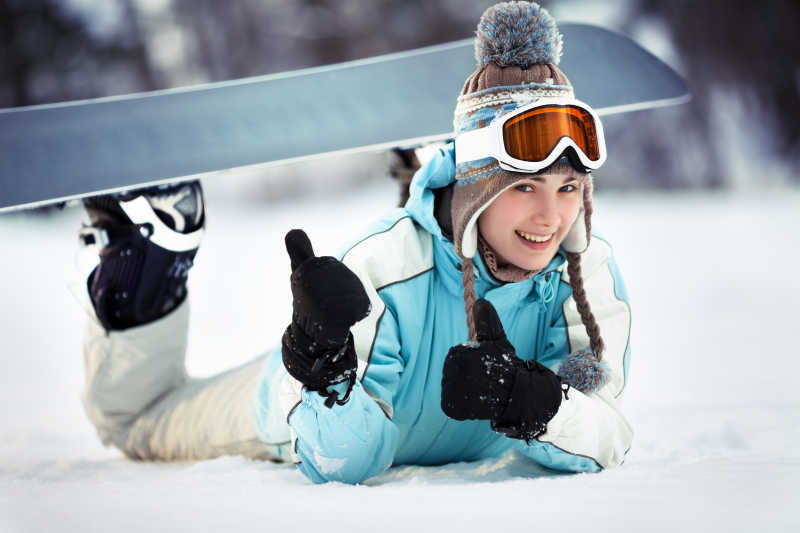 女性滑雪者趴在地上竖起了大拇指