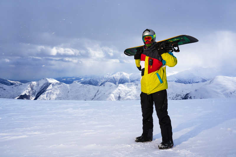 冬季雪山上拿着滑板特写