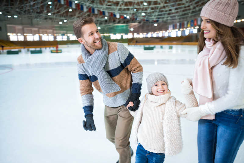 微笑的家庭成员在体育馆溜冰