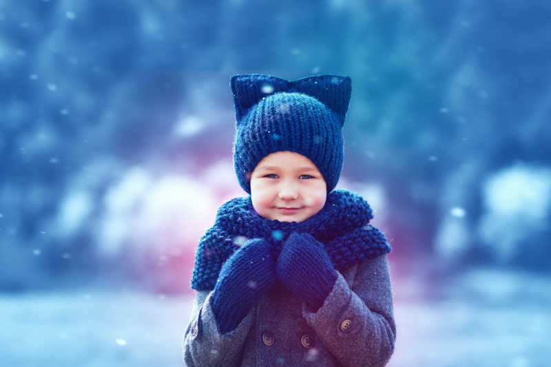 可爱的孩子戴着针织服装在下雪的冬天