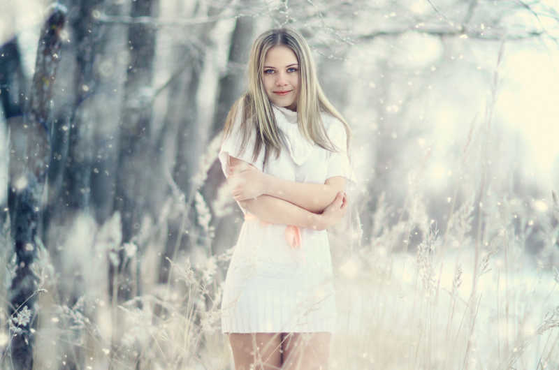 森林雪地里穿着短袖连衣裙的年轻女子