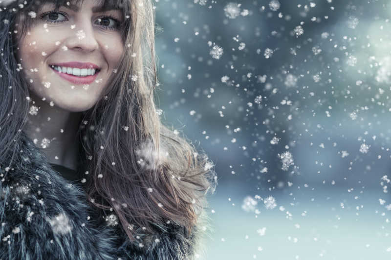 冬日下雪景里微笑的年轻女孩肖像