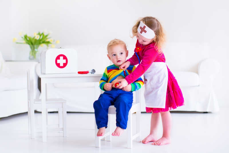 两个可爱的蹒跚学步的女孩和可爱的男婴扮演医生与病人进行游戏