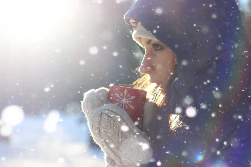 下雪户外装备整齐的女孩捧着热咖啡