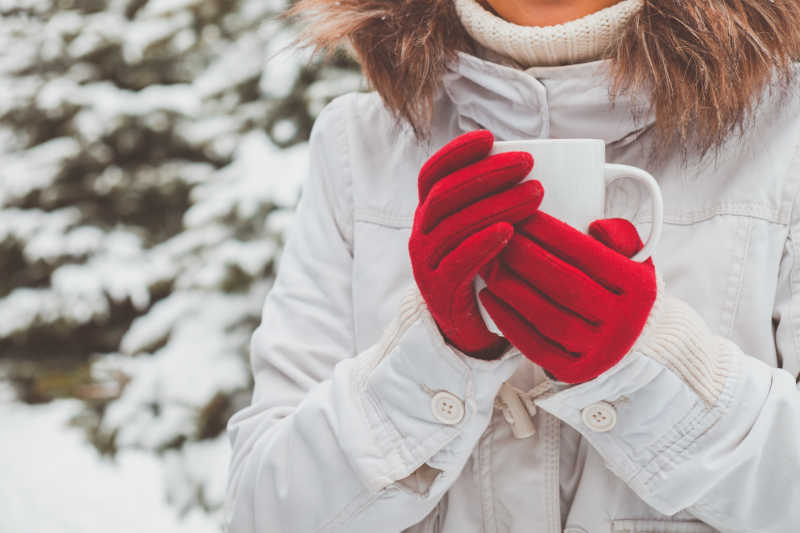 冬季下着雪的户外戴着红色手套捧着咖啡杯的特写