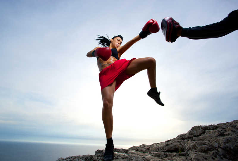 美丽有力量的拳击女性运动员在大自然中进行高踢腿训练