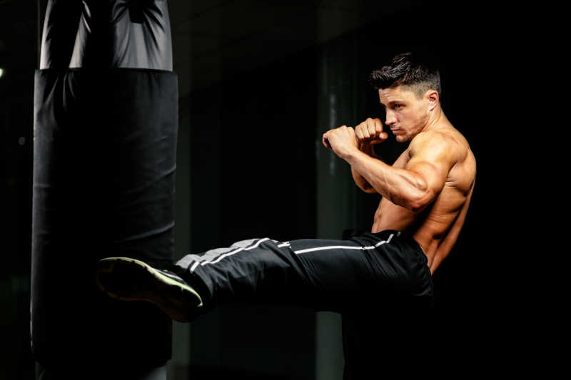 肌肉健壮的拳击手在拳击袋上训练