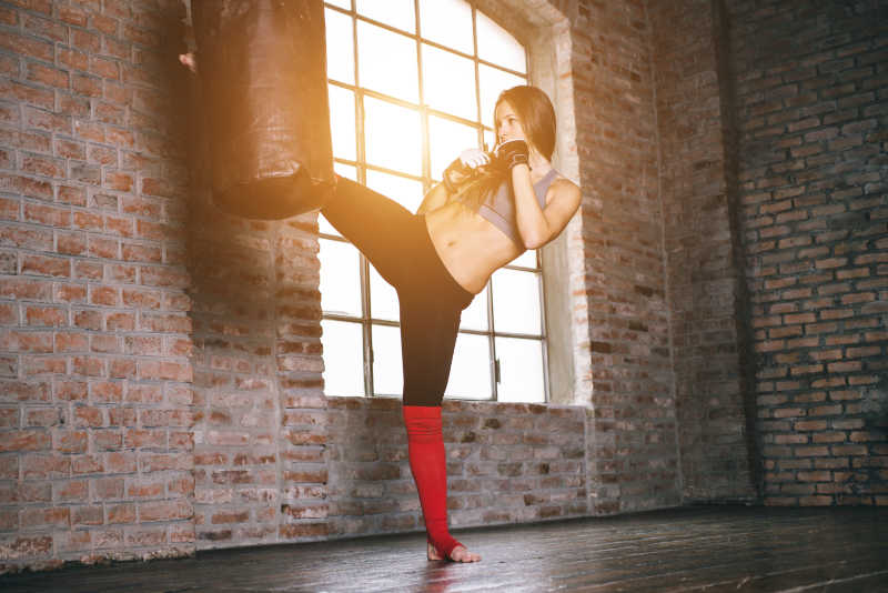 女人在跆拳道利用沙袋训练腿部力量