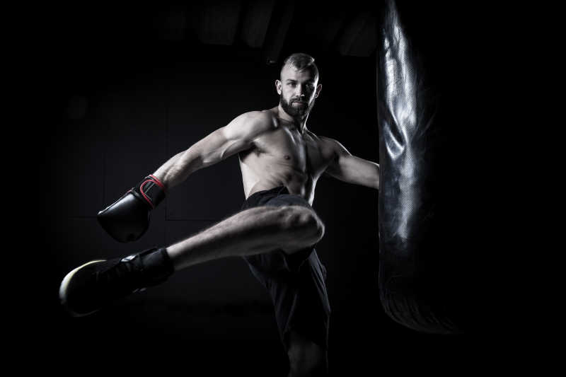男性拳击运动员利用拳击袋练习踢腿