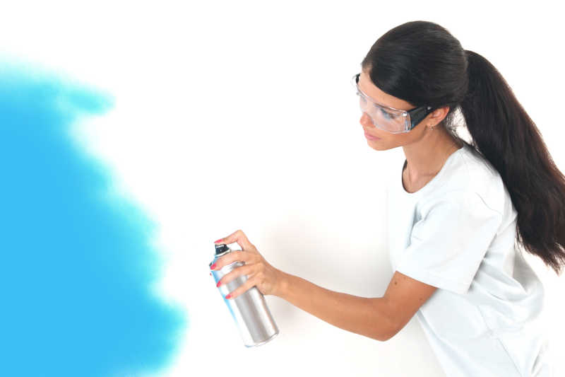 女人使用喷漆往墙上喷油漆