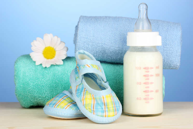 婴儿奶瓶毛线鞋和蓝色背景上的毛巾