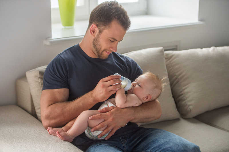 肌肉发达的爸爸抱着宝宝喂奶粉