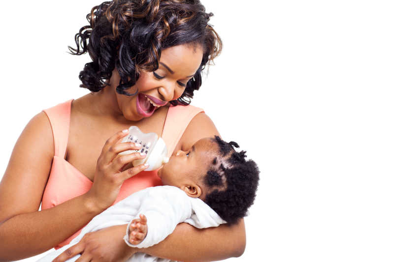 快乐幸福的非洲裔美国母亲用奶瓶喂她的小女孩