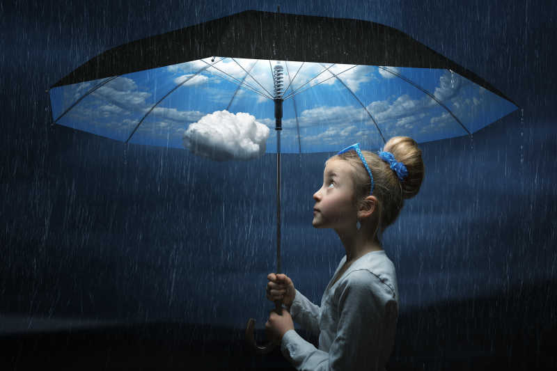 下雨的天气里小女孩撑着里面是蓝天白云的伞特写