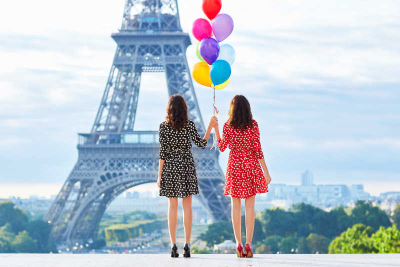双胞胎姐妹拿着气球站在诶菲尔铁塔旁