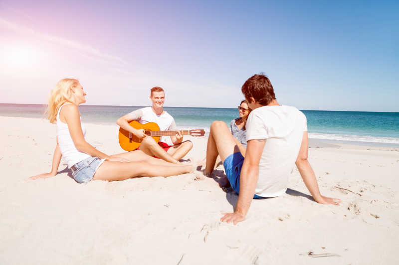 沙滩上弹吉他听歌的年轻朋友