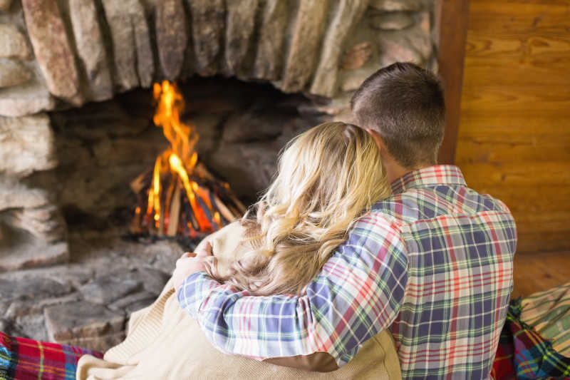 一对浪漫的年轻夫妇坐在壁炉前