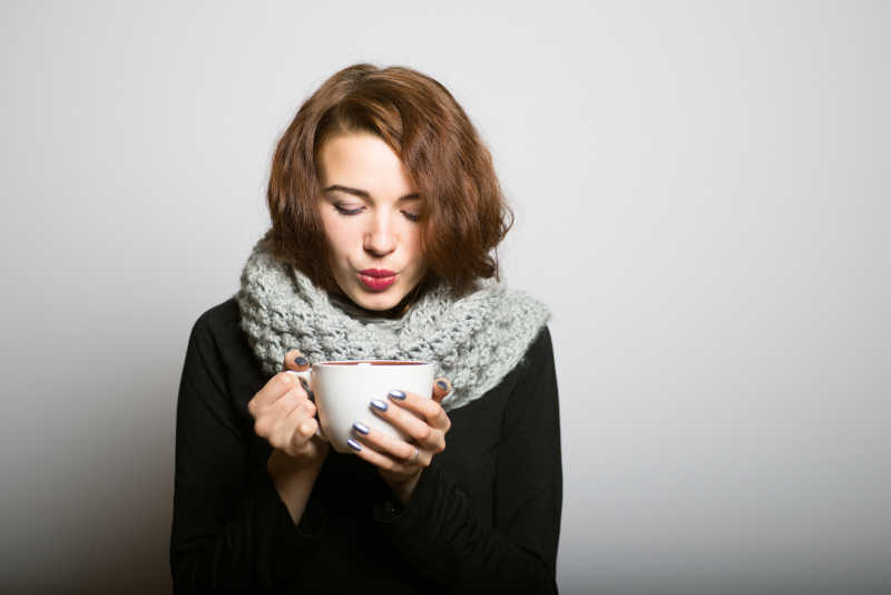 美丽的女孩在冬天喝咖啡或茶保持温暖