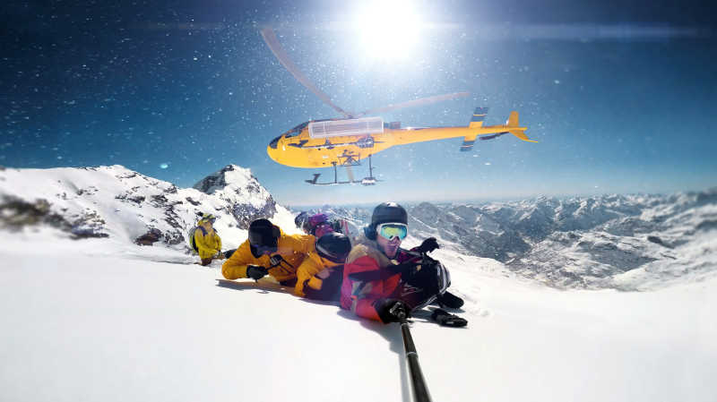 滑雪板掉落在山顶的一架直升机和一个人正在与广角相机微笑selfie
