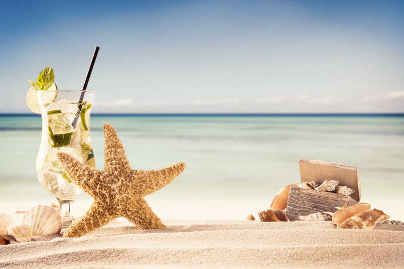 夏日海滩有一杯饮料一箱贝壳和一个海星